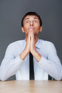 Profile shot of professional man holding hands up to face agains